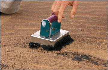 Chris zeigt mit einem Magneten den Eisengehalt des Sandes.